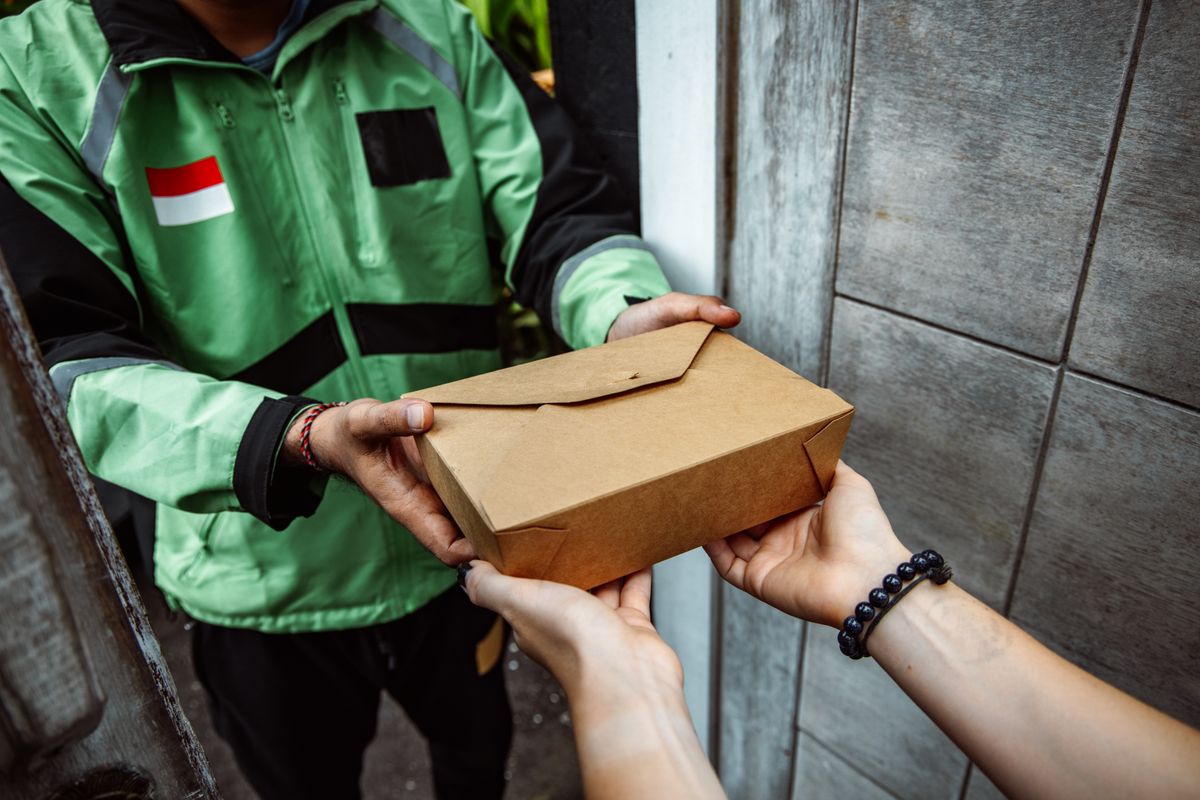 A food delivery handoff in a cardboard lunchbox
