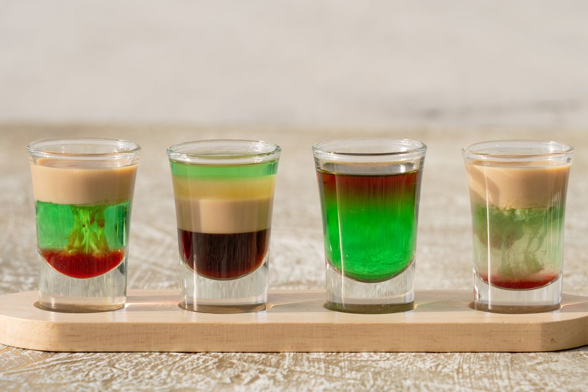 Colorful layered party shots arranged on a wooden tray