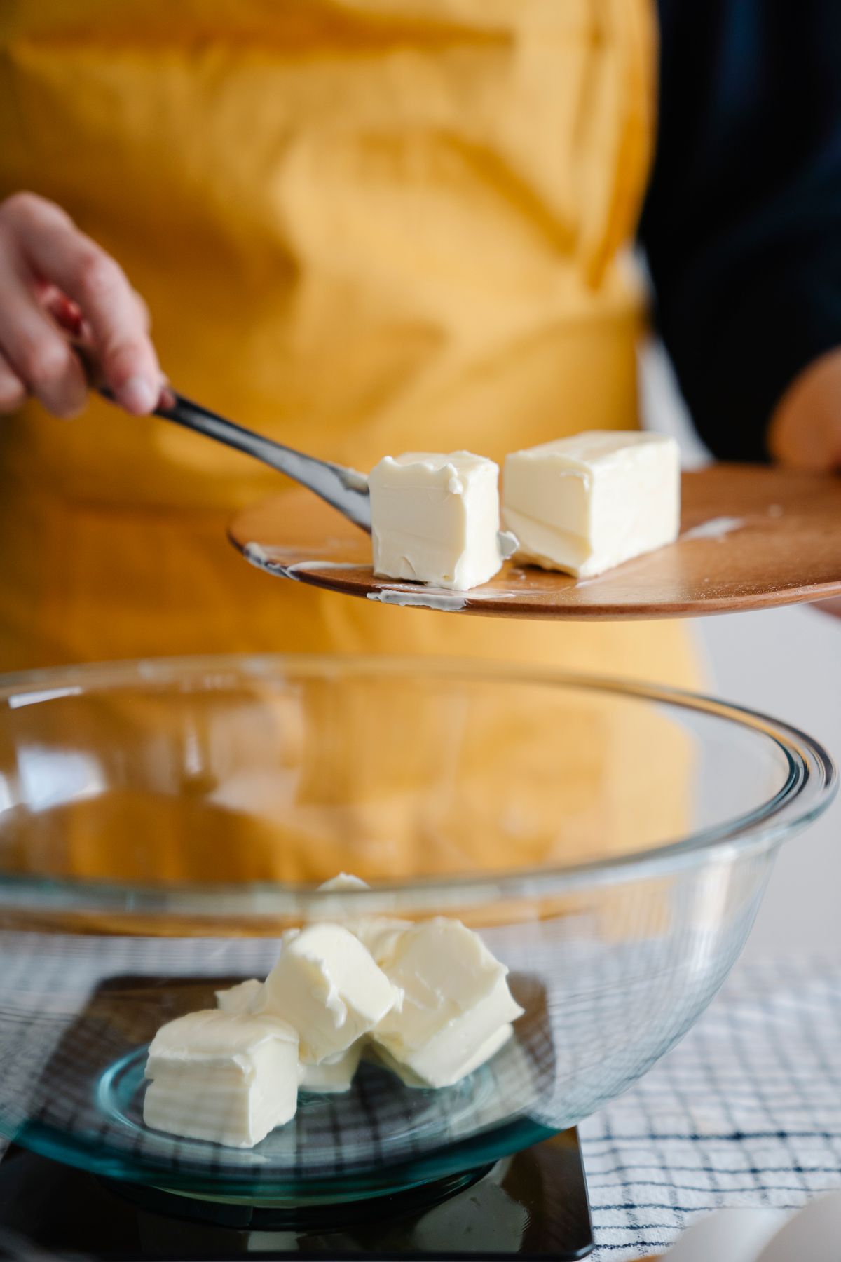 Hands adding cubes of butter to a mixing bowl
